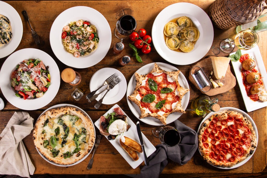 dinner table with pizzas, pastas, appetizers and wine